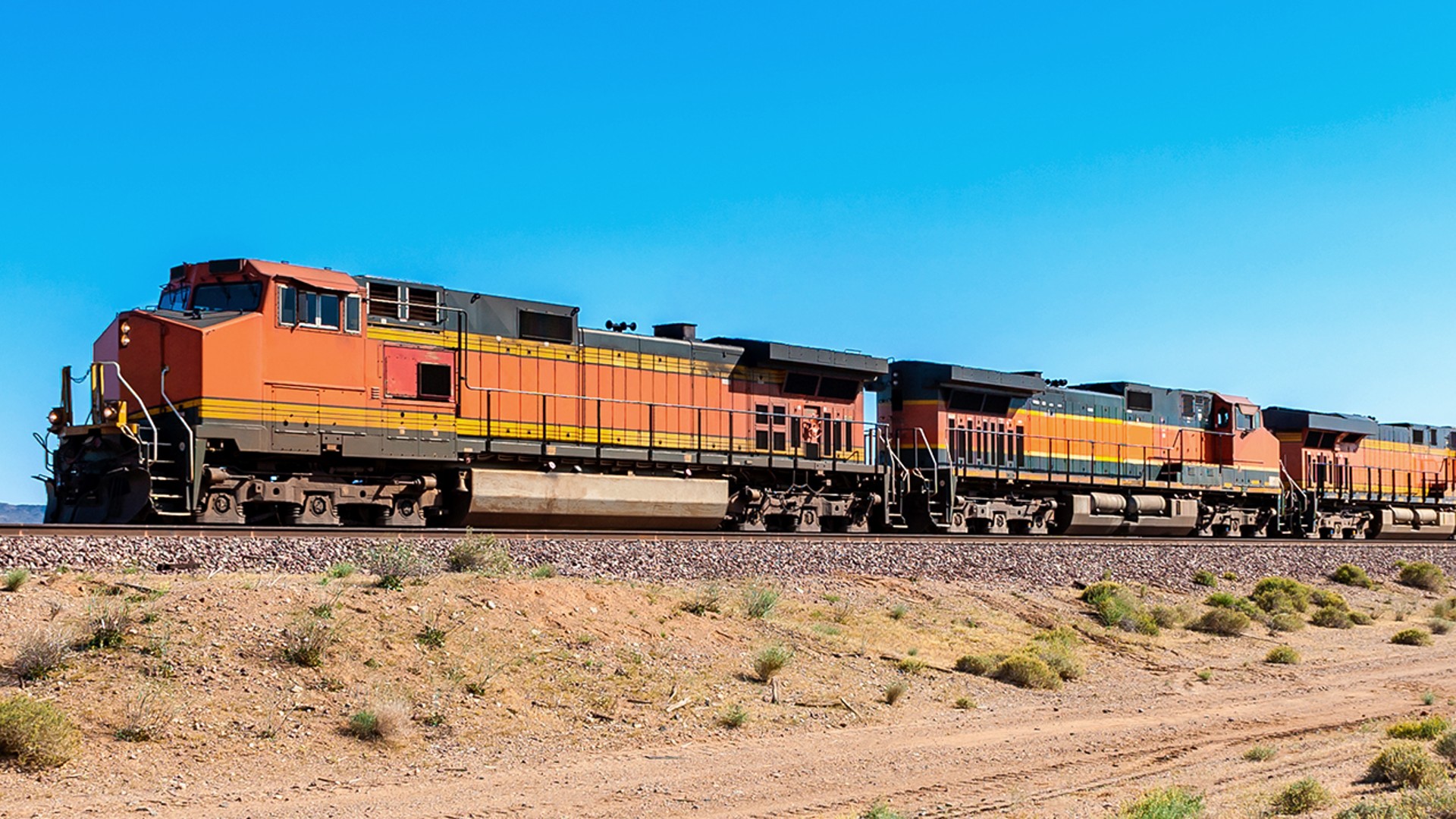 Freight train traveling across arid landscape.