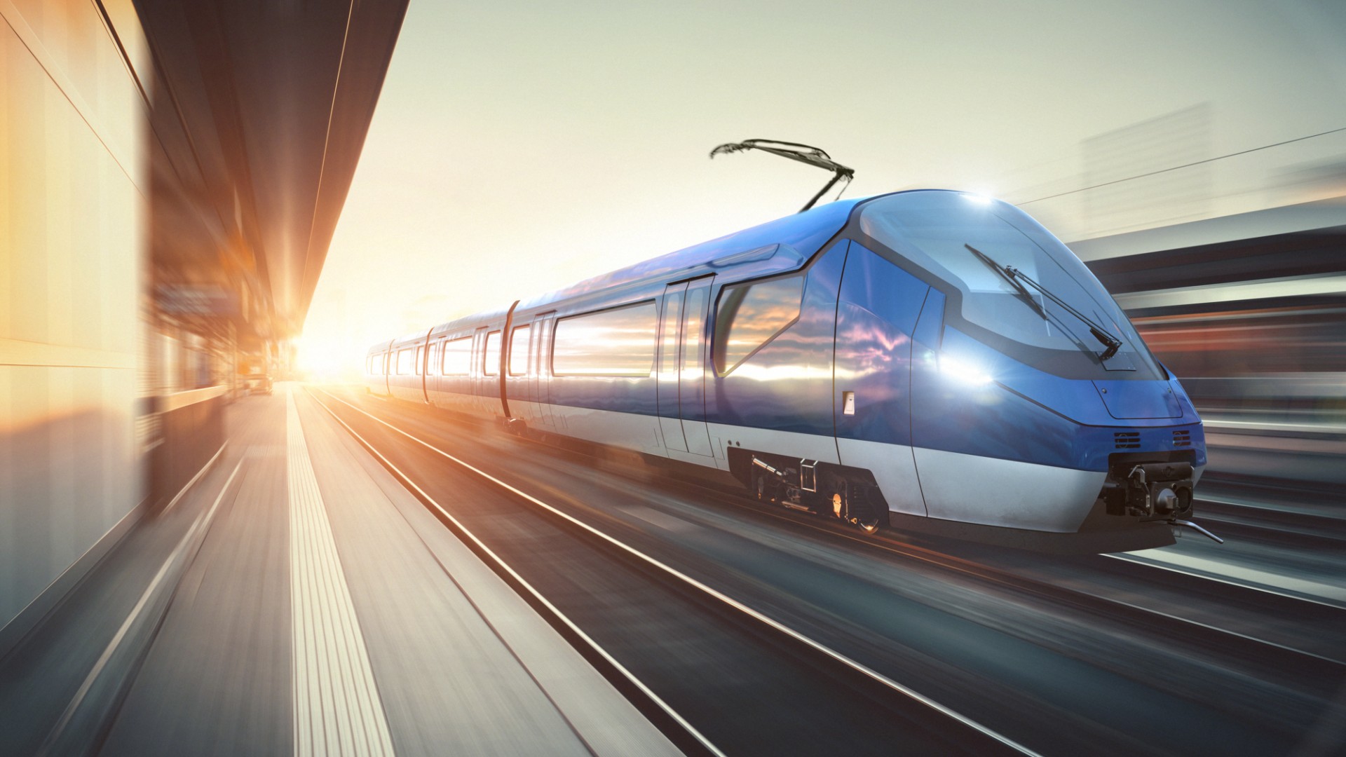 Fast-moving blue train on urban tracks.