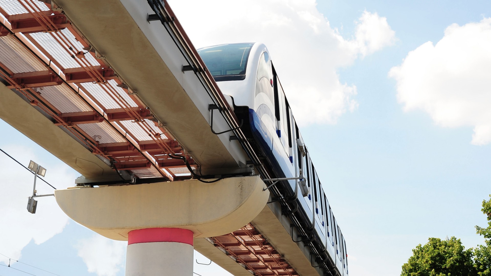Monorail train on elevated track against blue