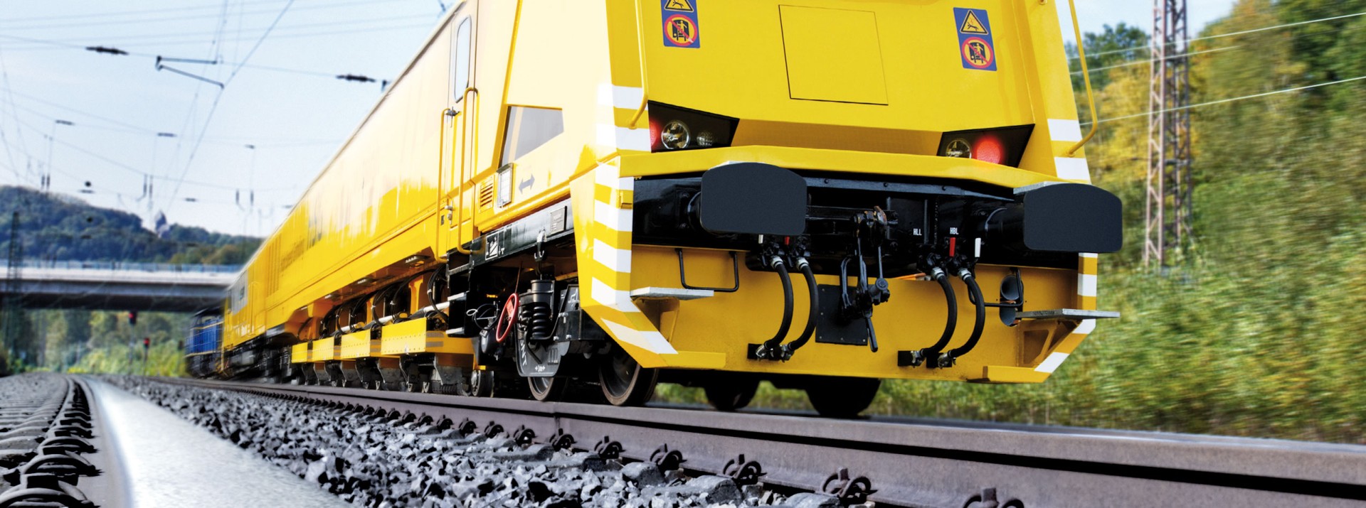 Yellow railway maintenance vehicle moving on tracks.