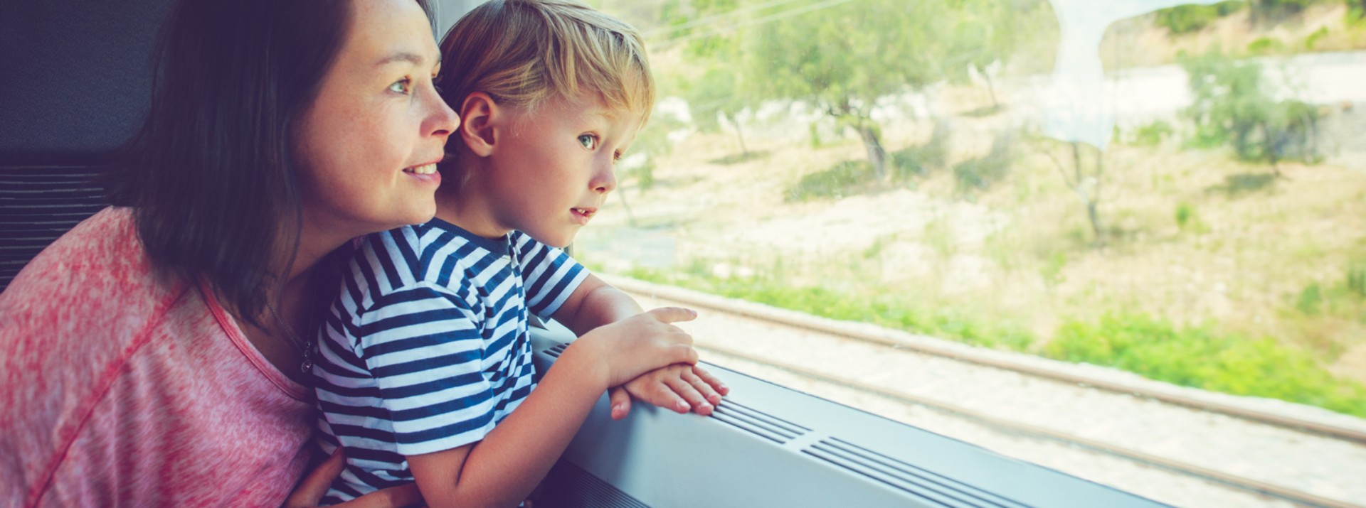 Mother and child gazing out train window.