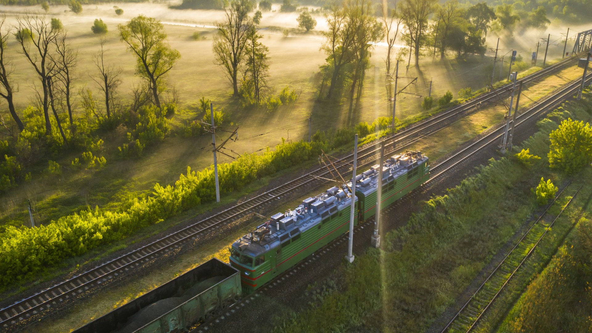 Train on tracks surrounded by misty landscape.