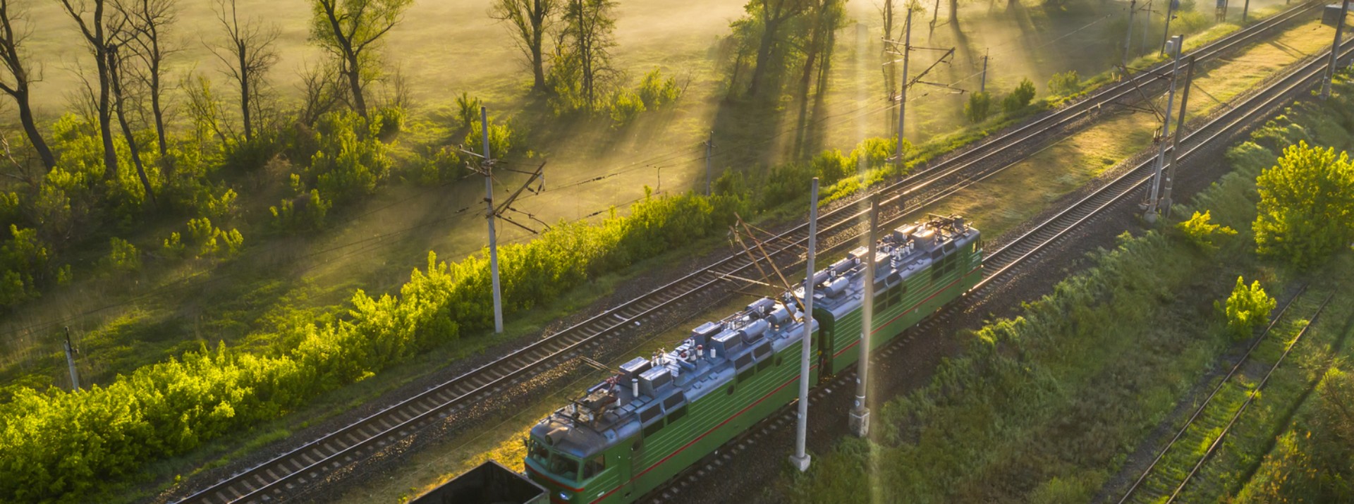 Train on tracks surrounded by misty landscape.