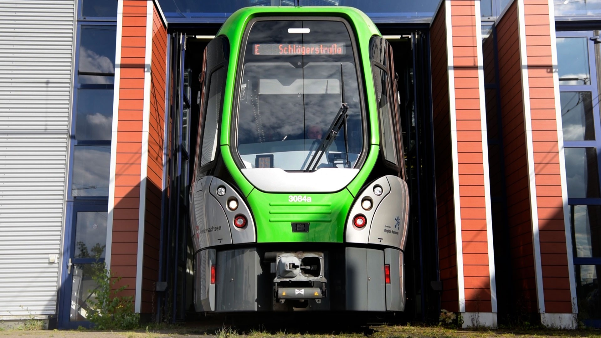 Green tram exiting a modern transport facility.