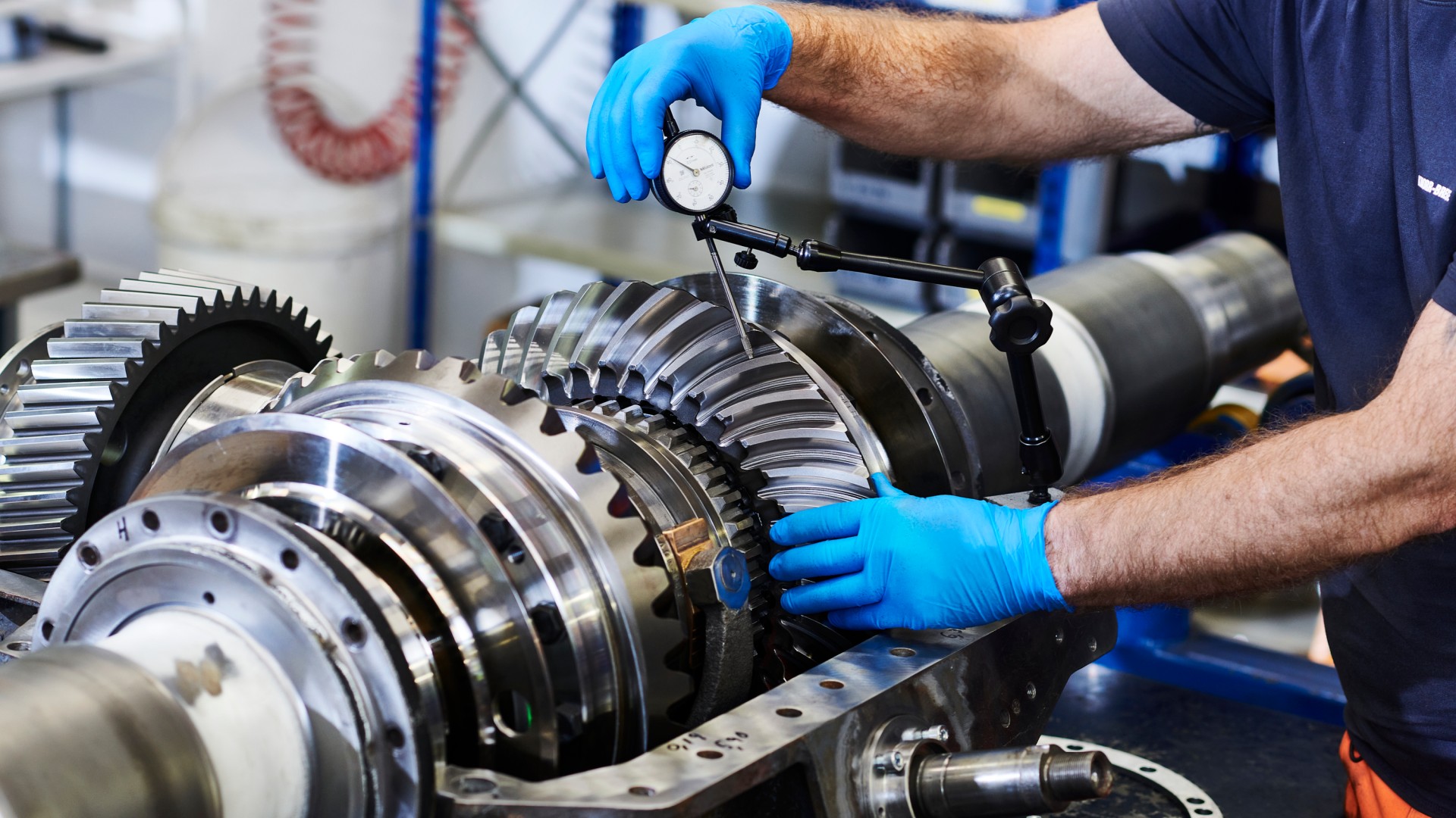 Employee measuring gear components with precision tools