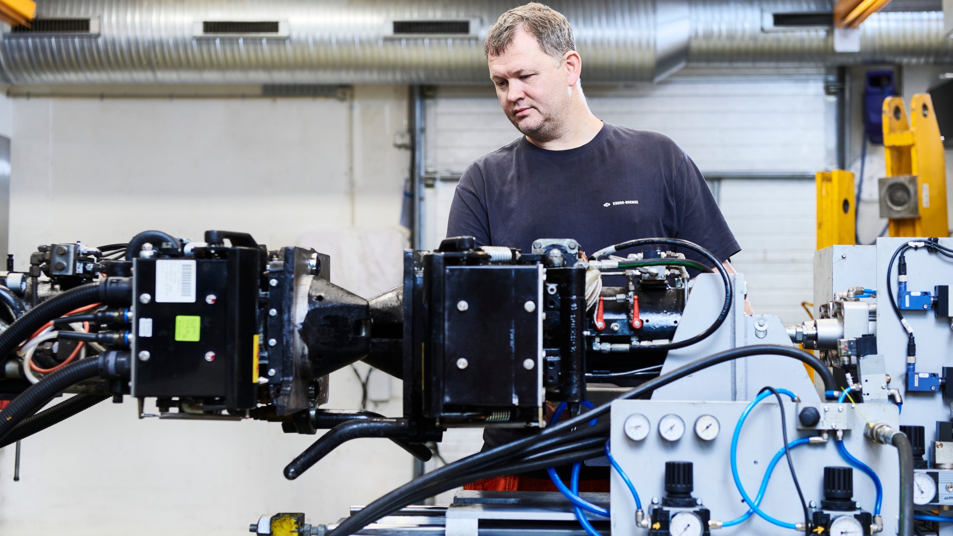 Male technician inspecting machinery in industrial workshop.