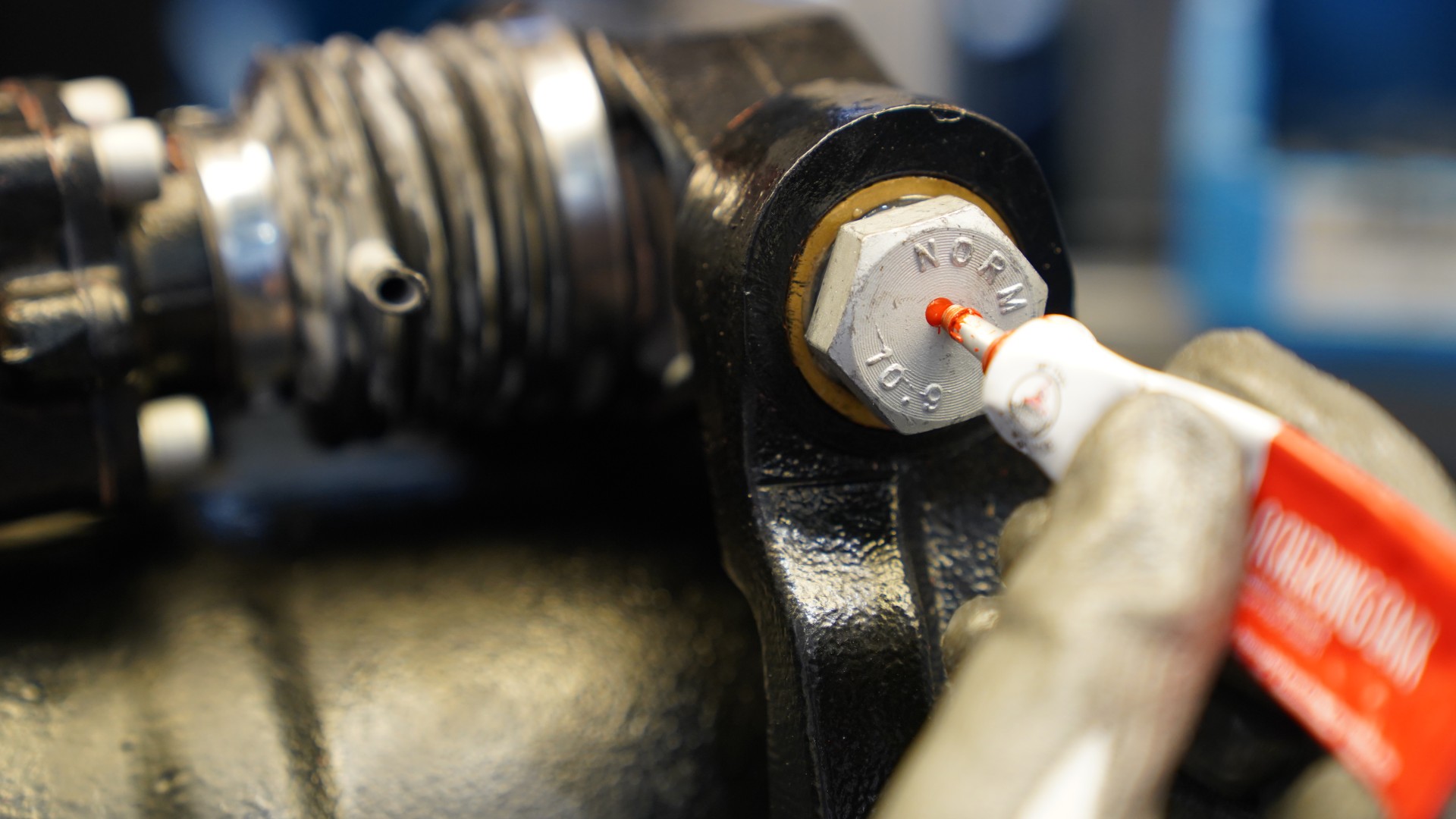 Applying red marker on a metal bolt