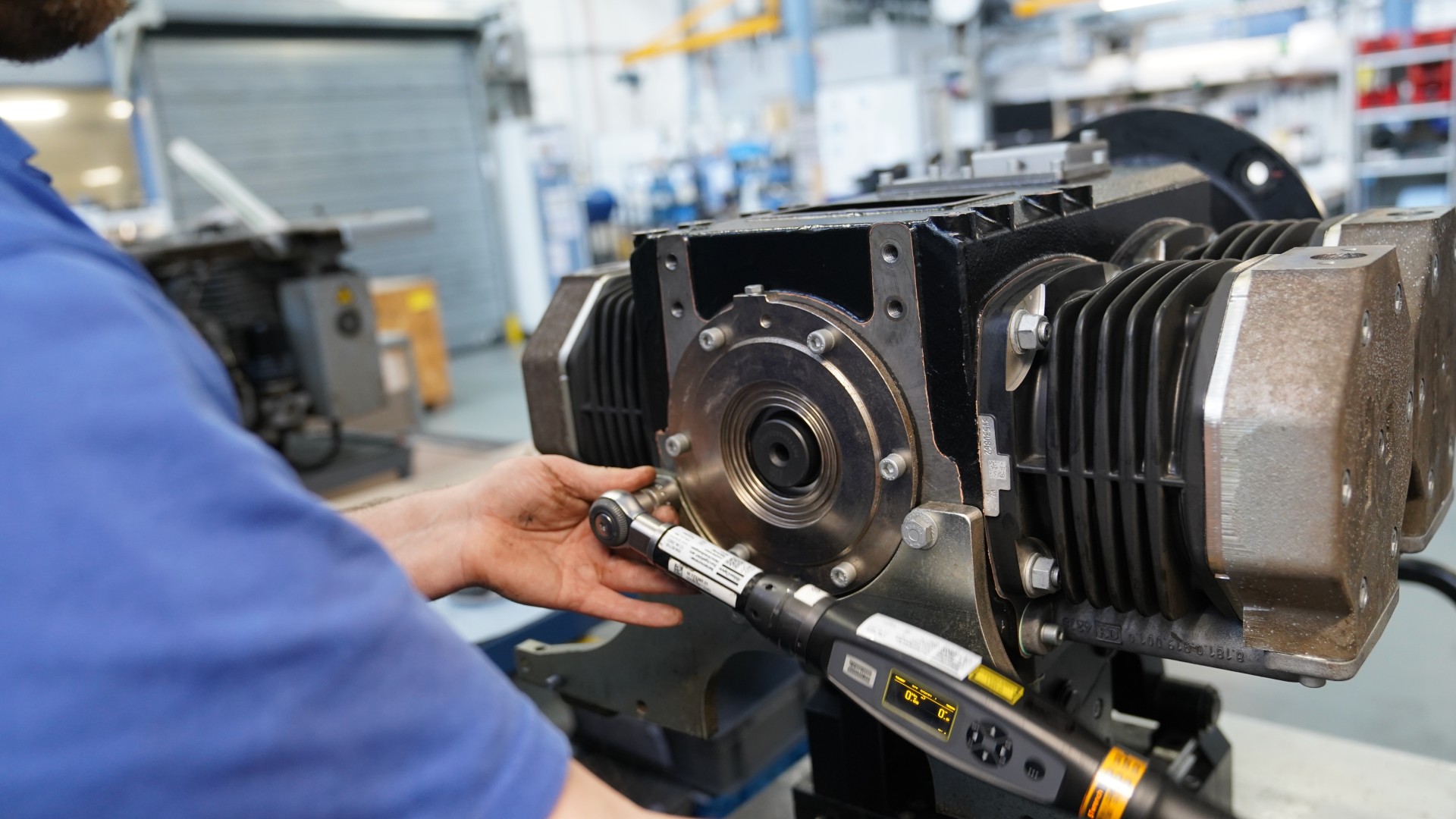 Technician using torque wrench on mechanical engine