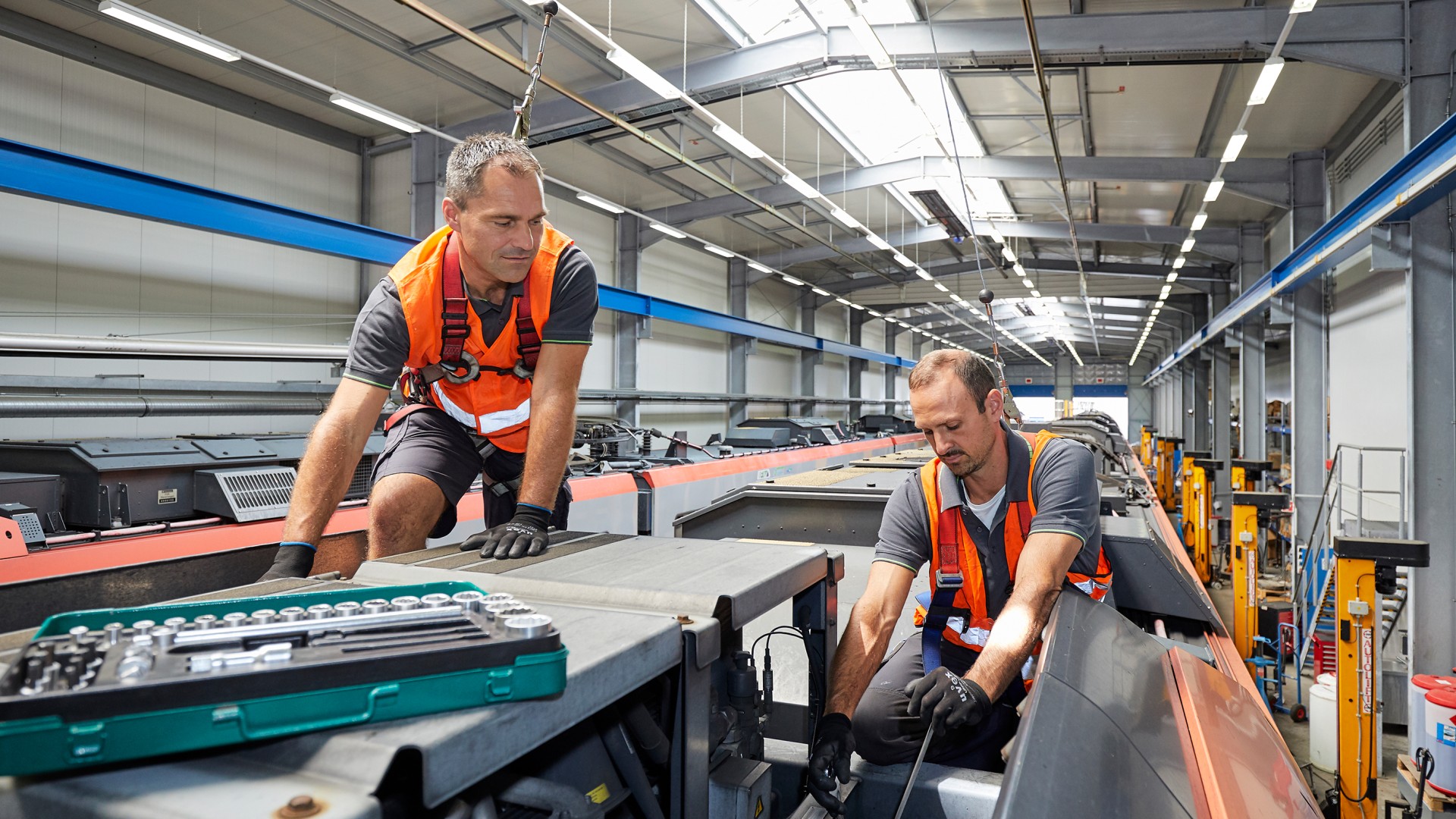 Two workers performing maintenance on train components.