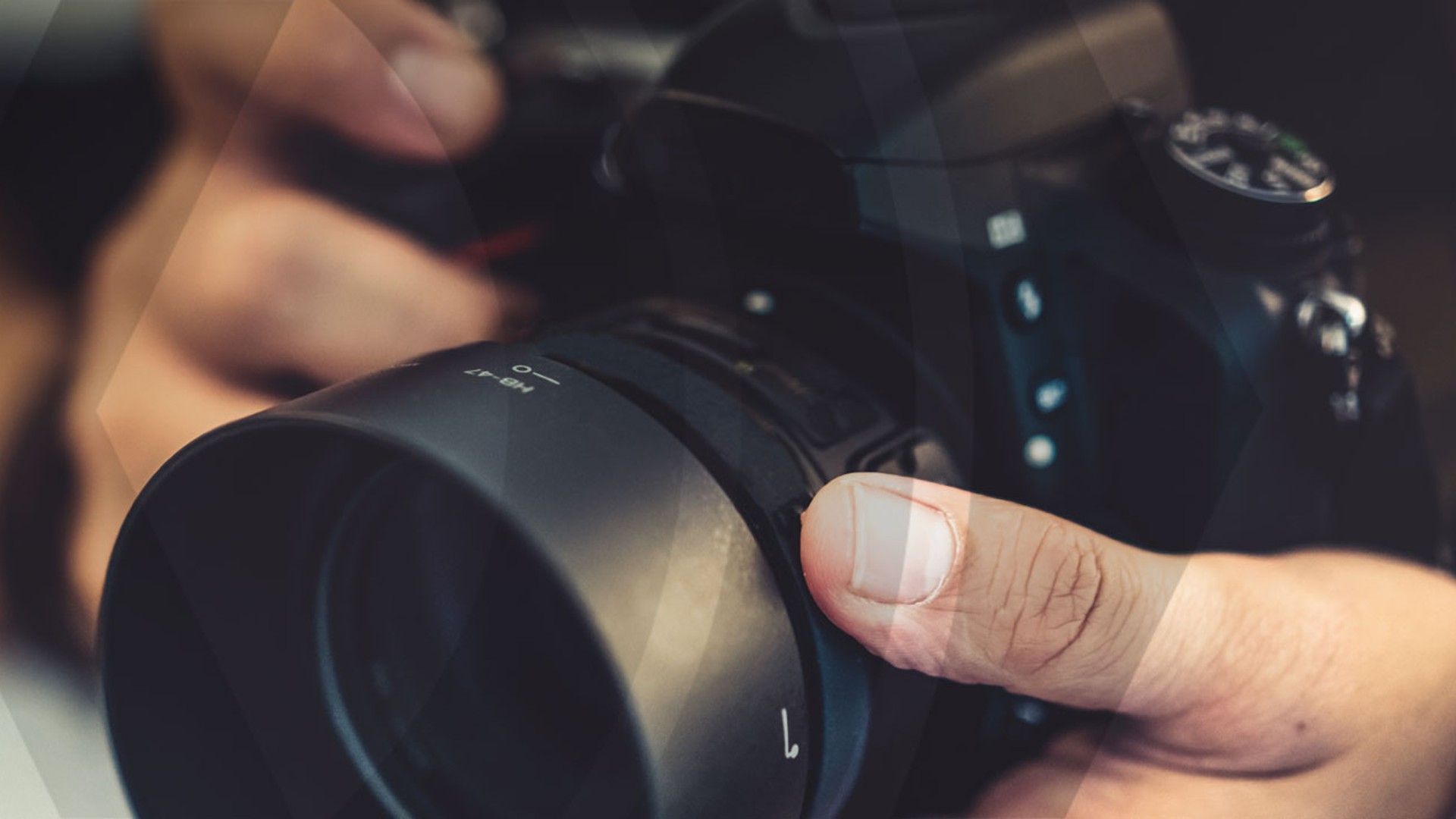 Person holding a camera with lens close-up.