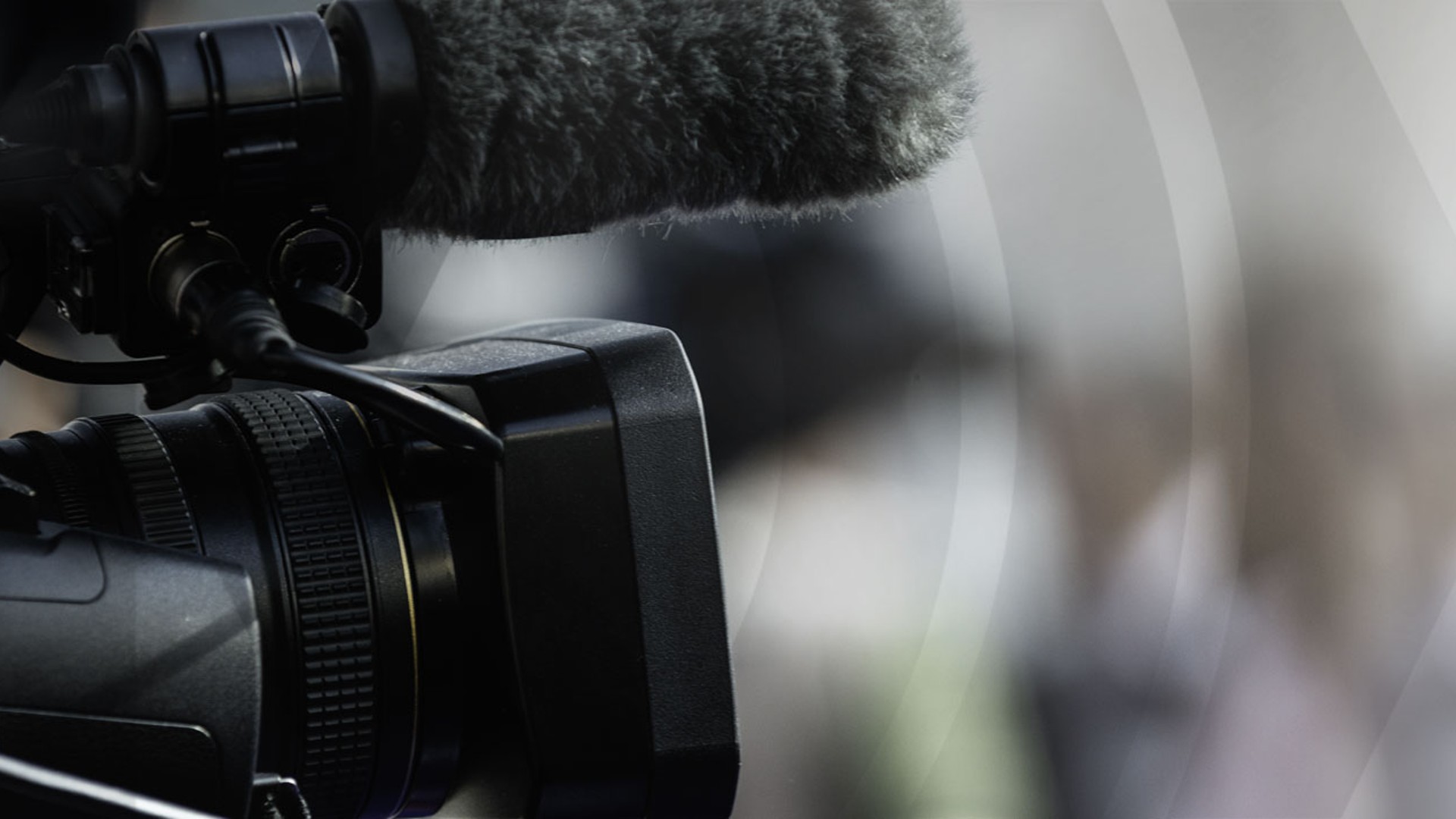 Video camera capturing interview scene with microphone.