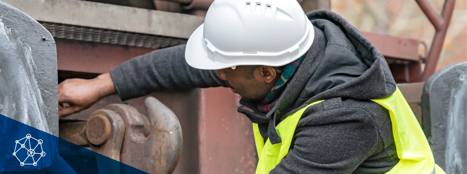 Worker inspecting railway equipment in safety gear.