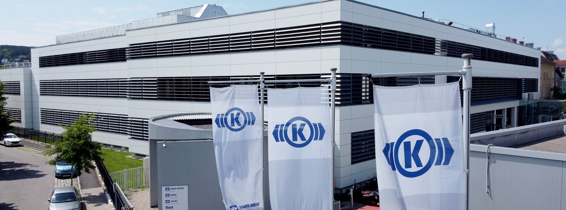 Knorr-Bremse building with branded flags and signage.