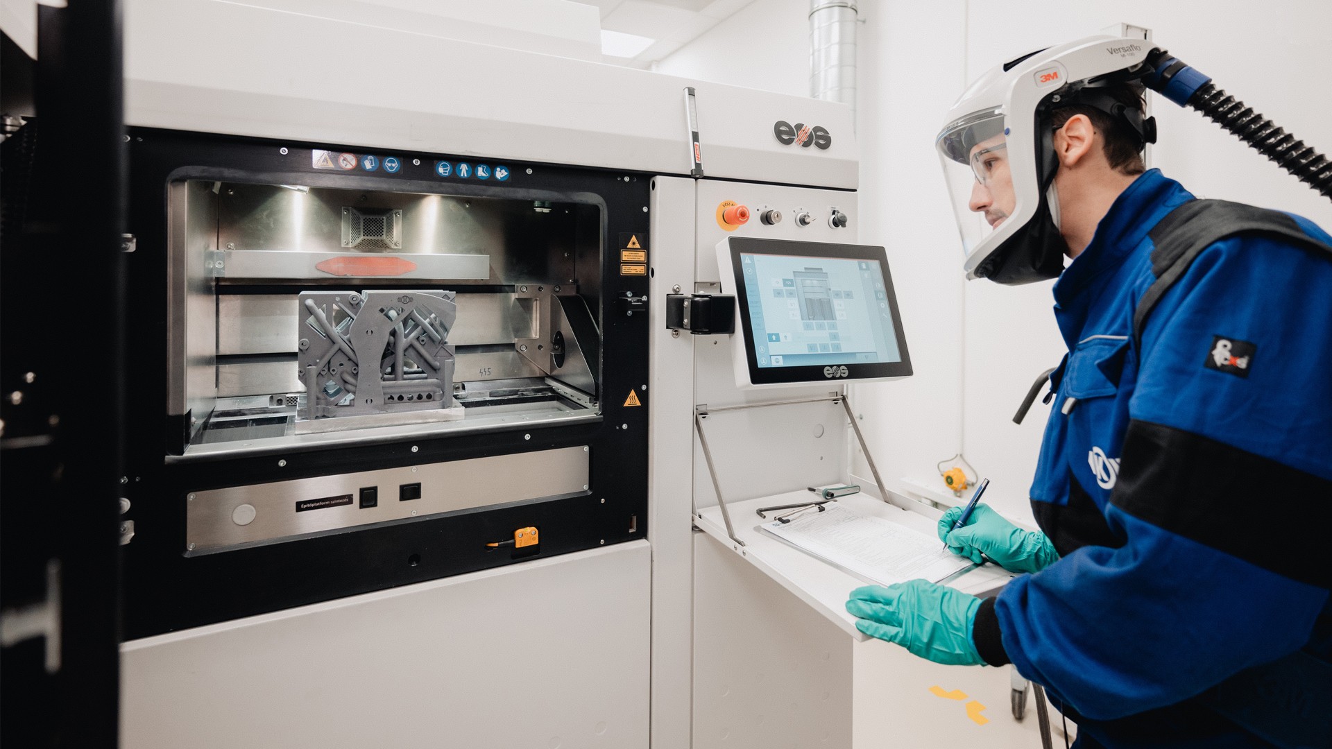 Employee operating industrial 3D printing machine.