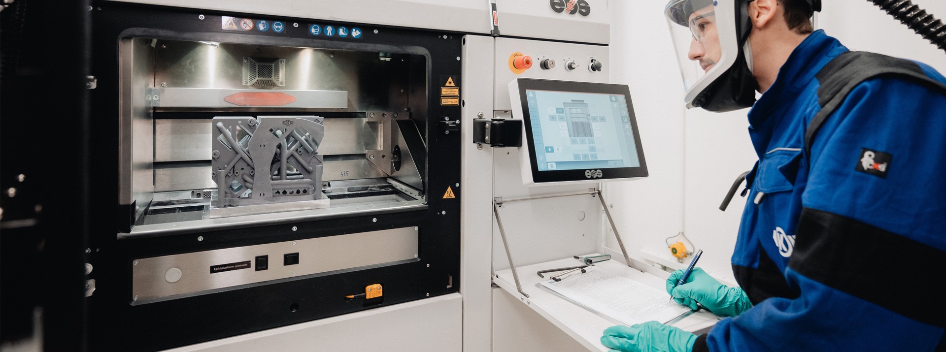 Employee operating industrial 3D printing machine.