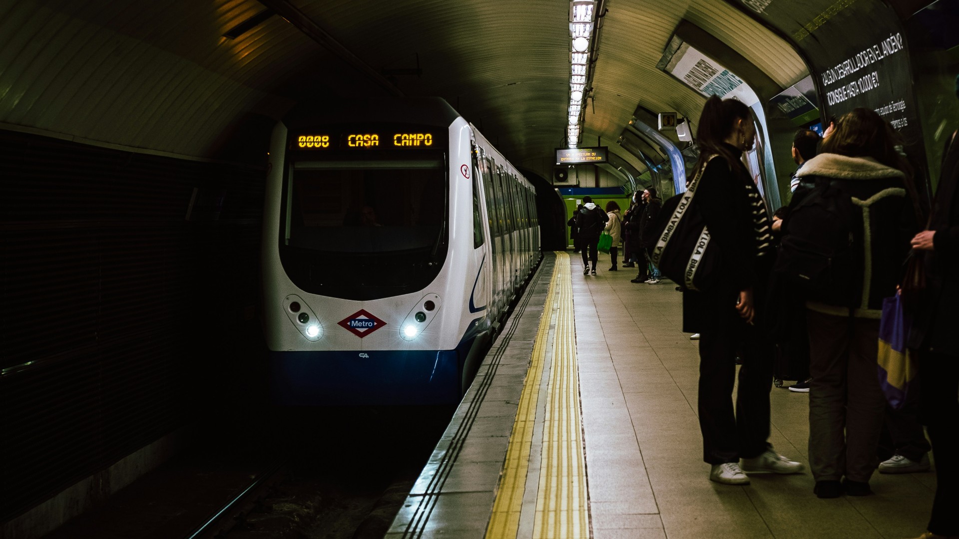 Metro train at platform with passengers waiting.