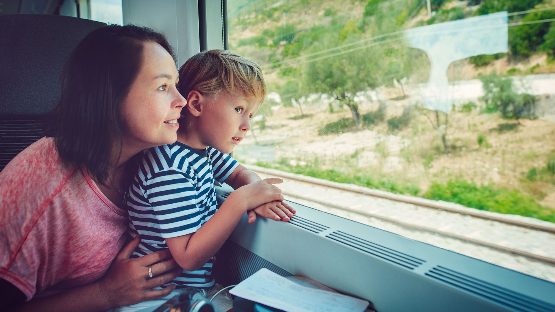 Mother and child looking out train window.