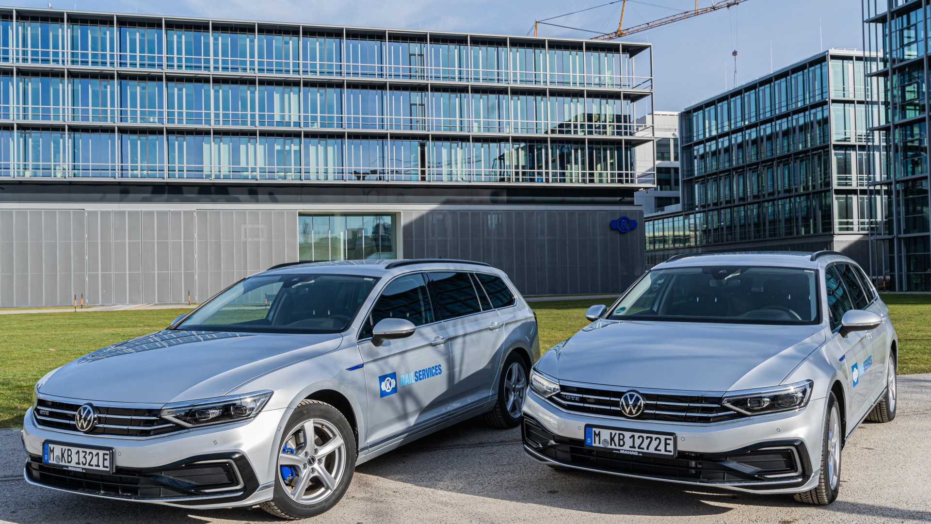 Two silver Volkswagen cars outside modern office