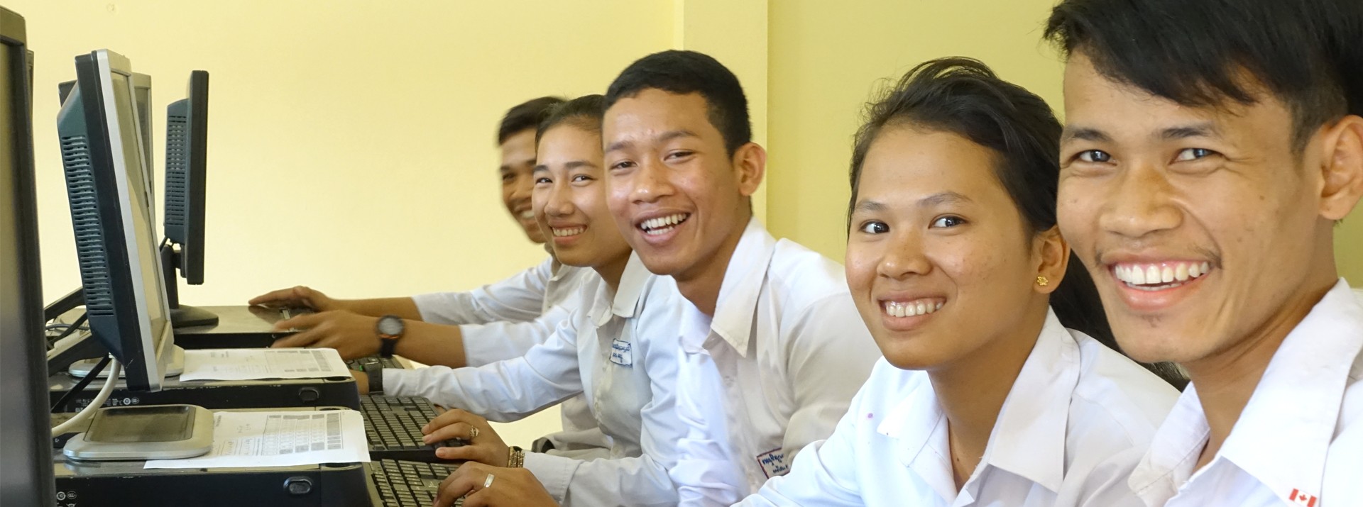 Group of smiling students working on computers.