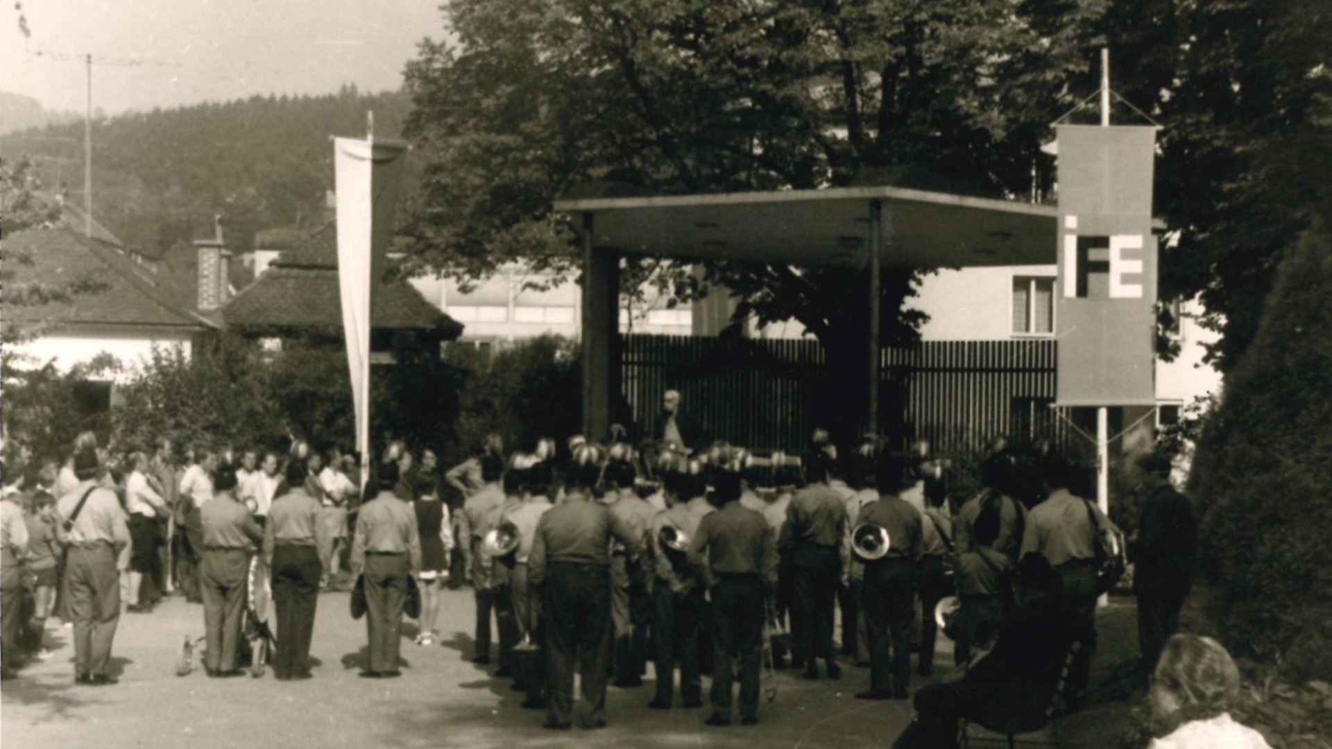 Historical gathering with attendees and speakers outdoors.