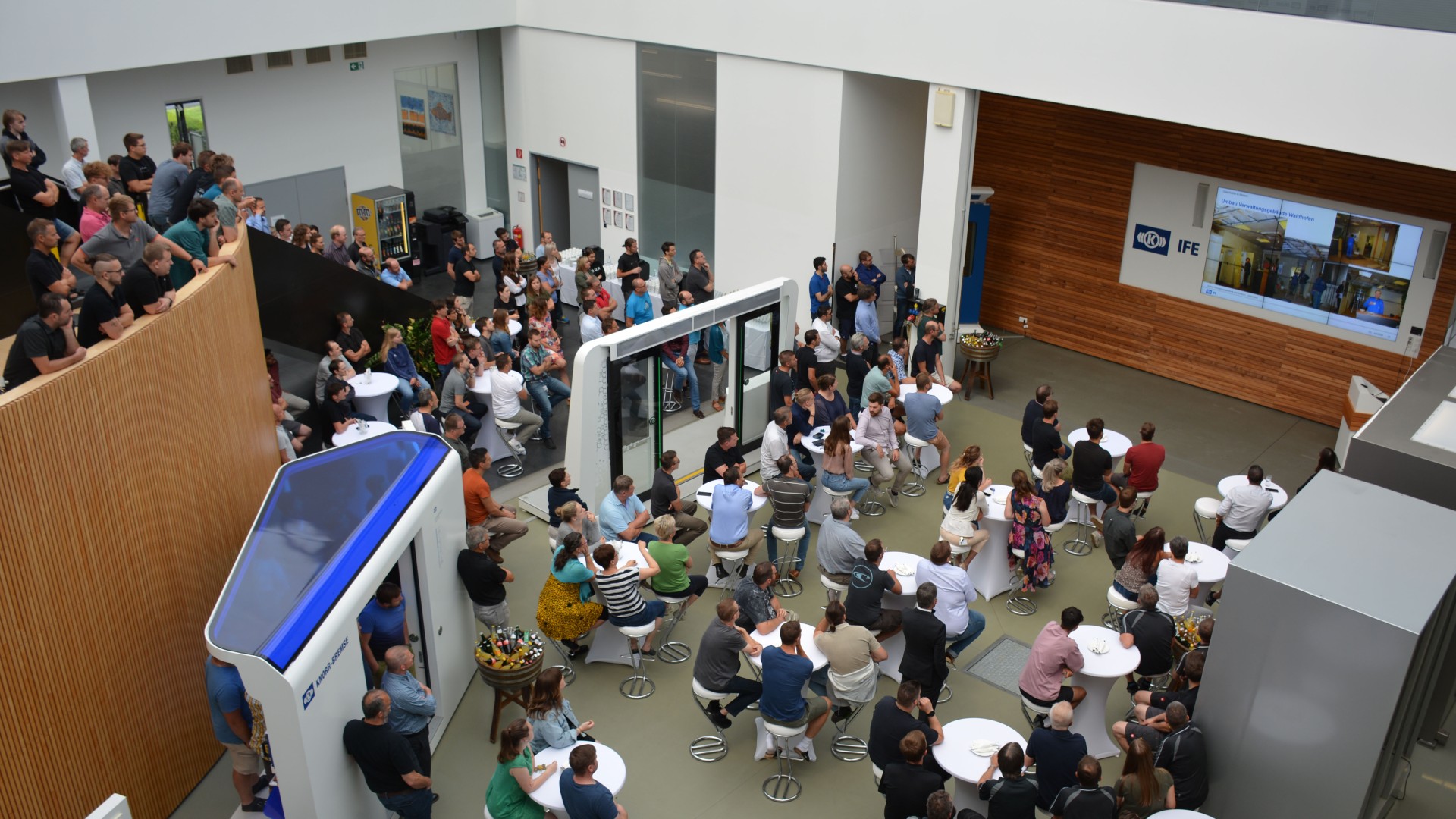 Crowded event space with attendees watching presentation.