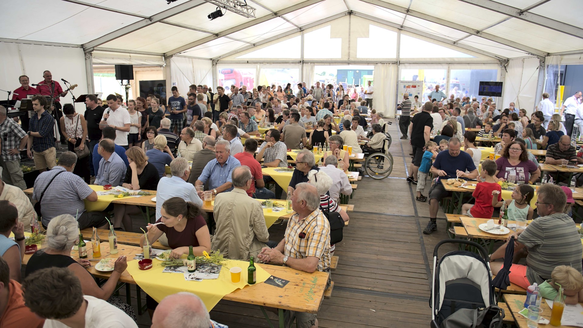 Crowded tent with people dining together.