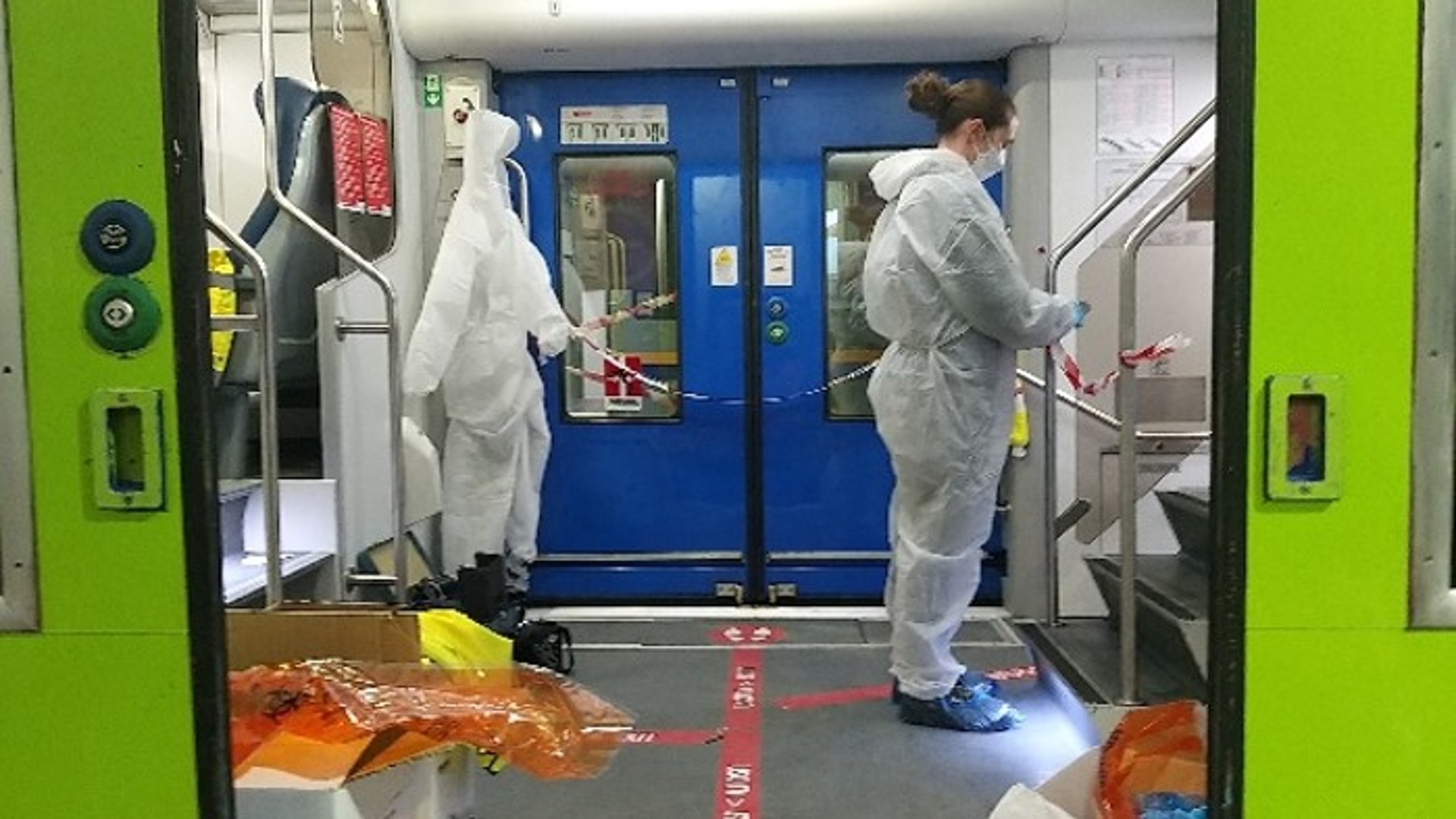 Workers in protective suits inside train carriage.