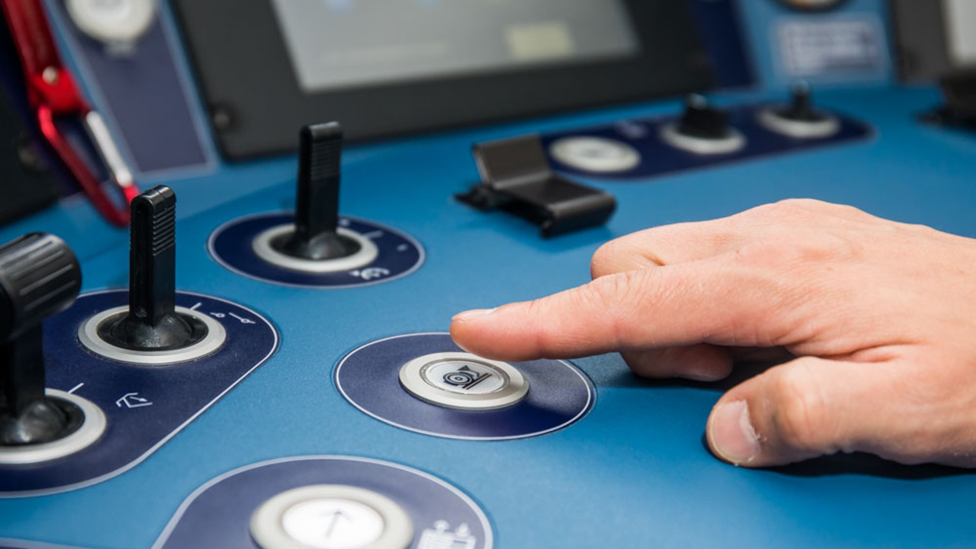 Hand pressing control button on blue panel.