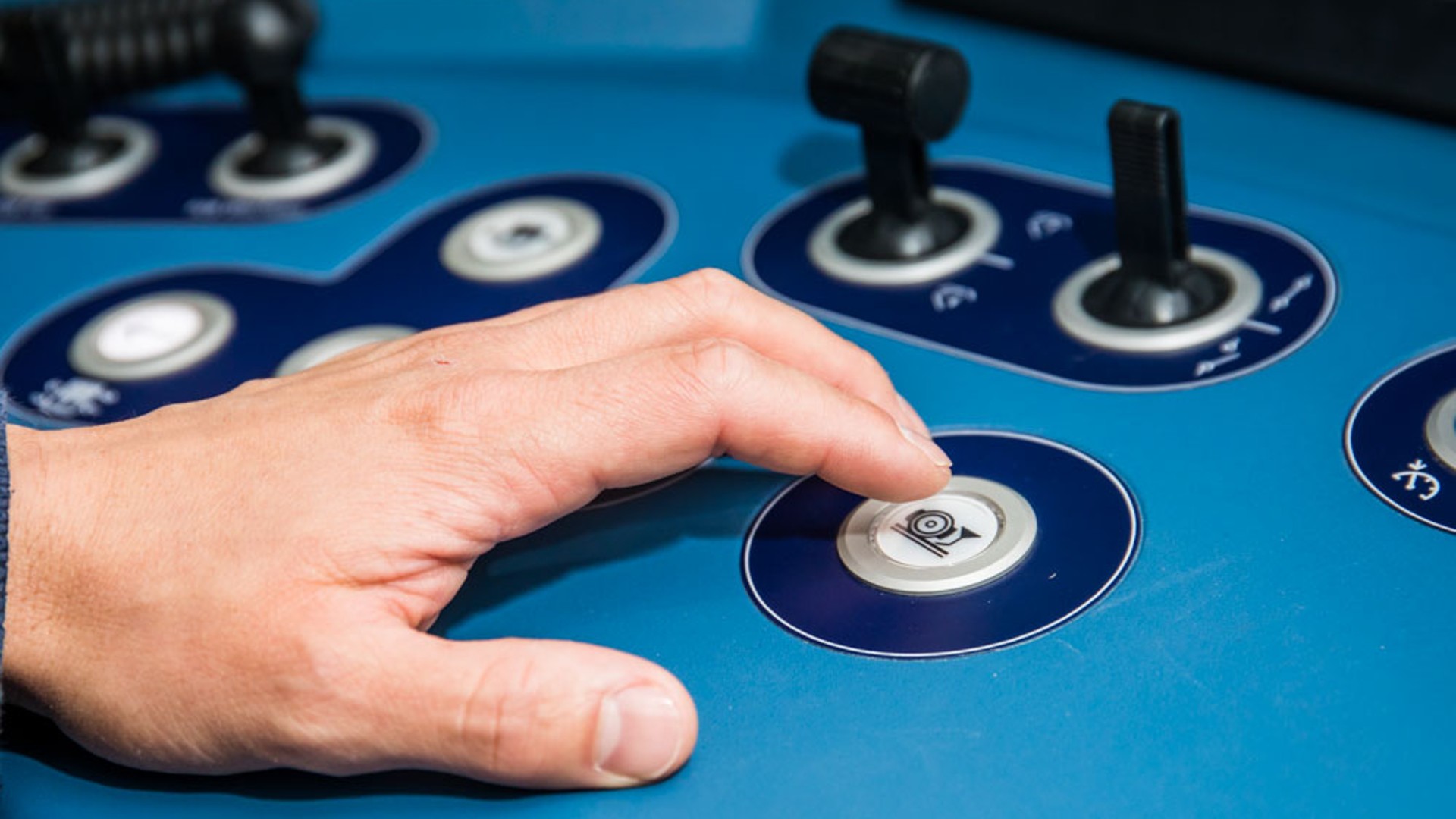 Hand pressing a control button on machinery.