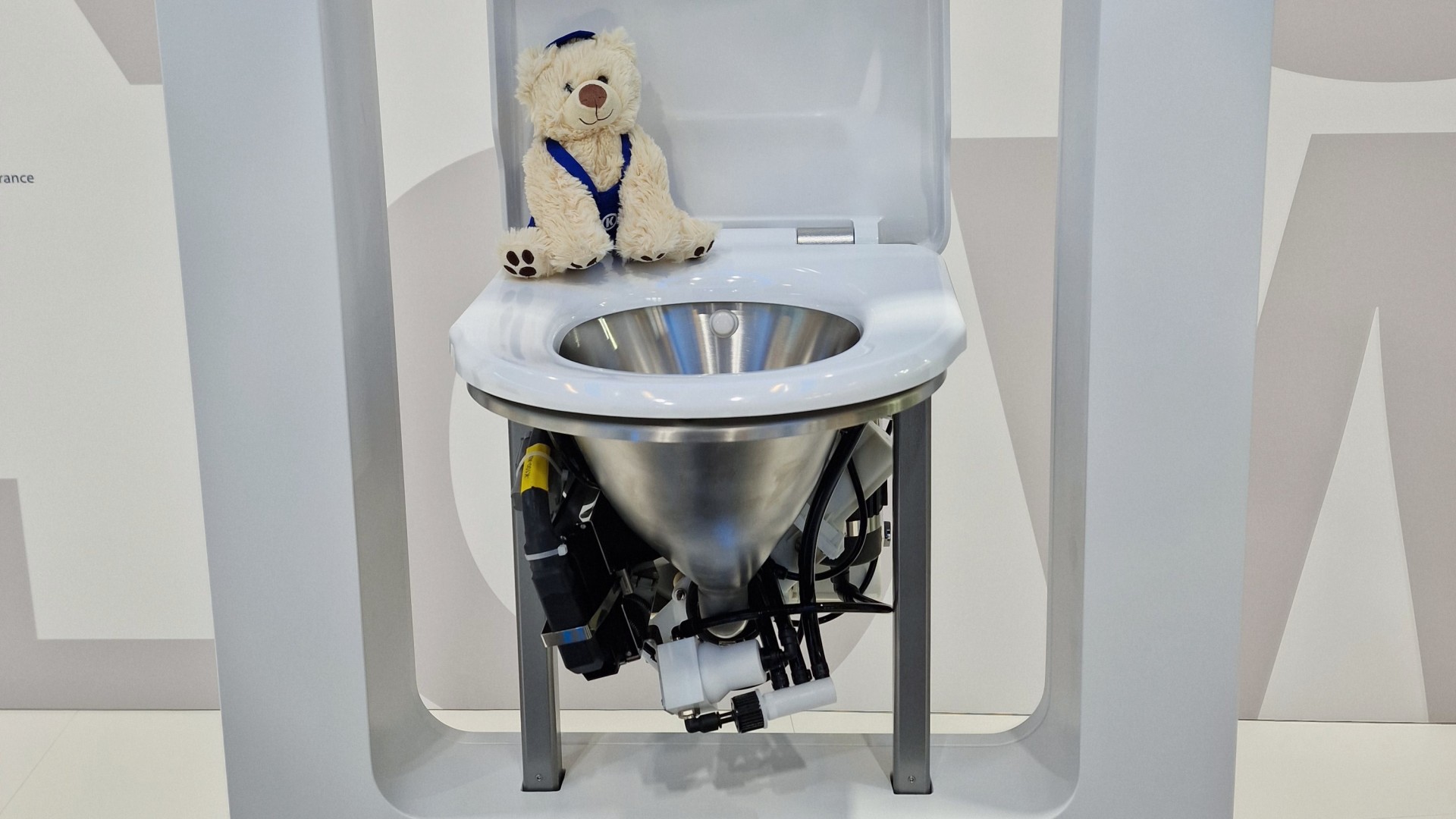 Plüschbär neben modernem Toilettendesign aus Edelstahl.