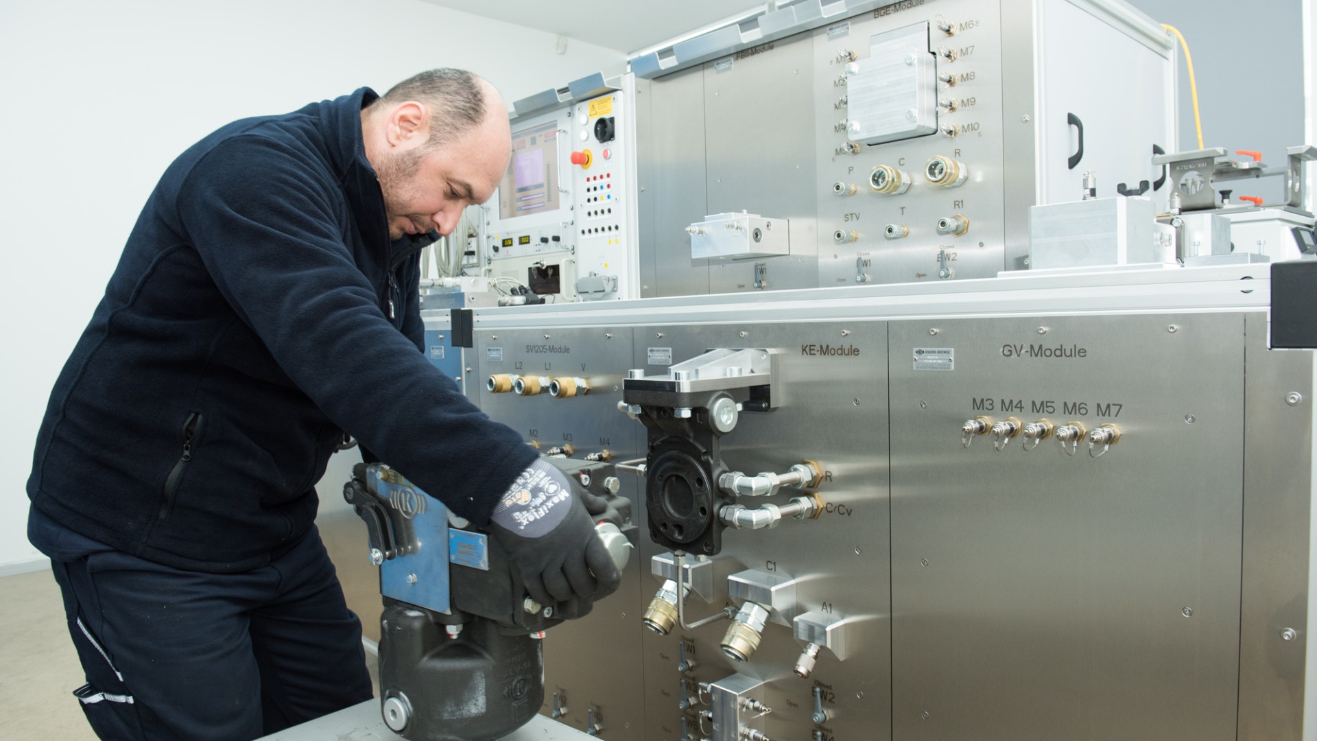 Technician adjusting hydraulic module on test equipment.
