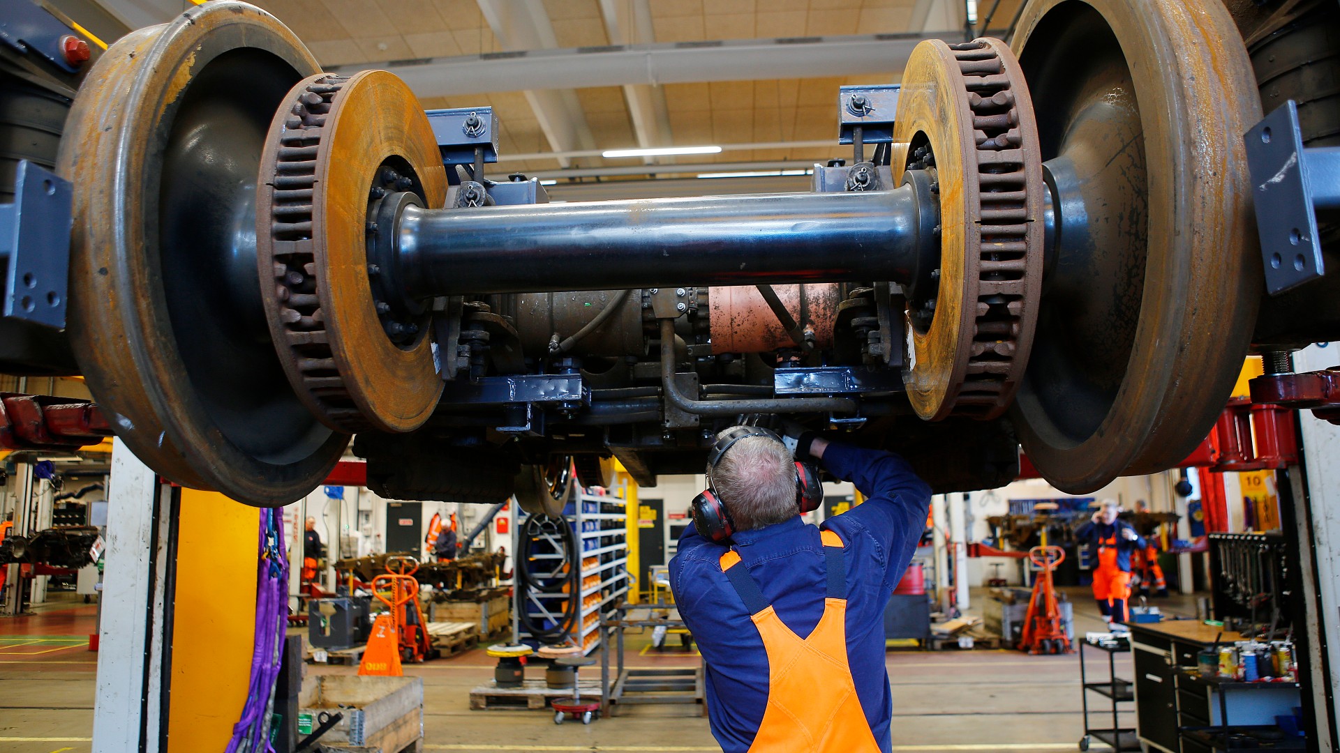 Employee inspecting train wheel assembly in workshop.