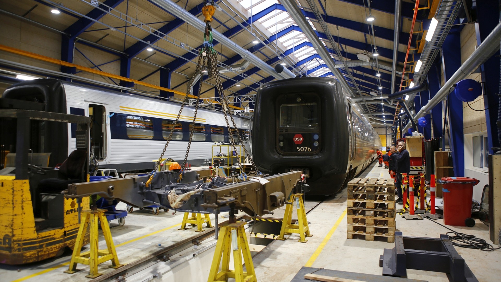 Train maintenance workshop with equipment and workers.
