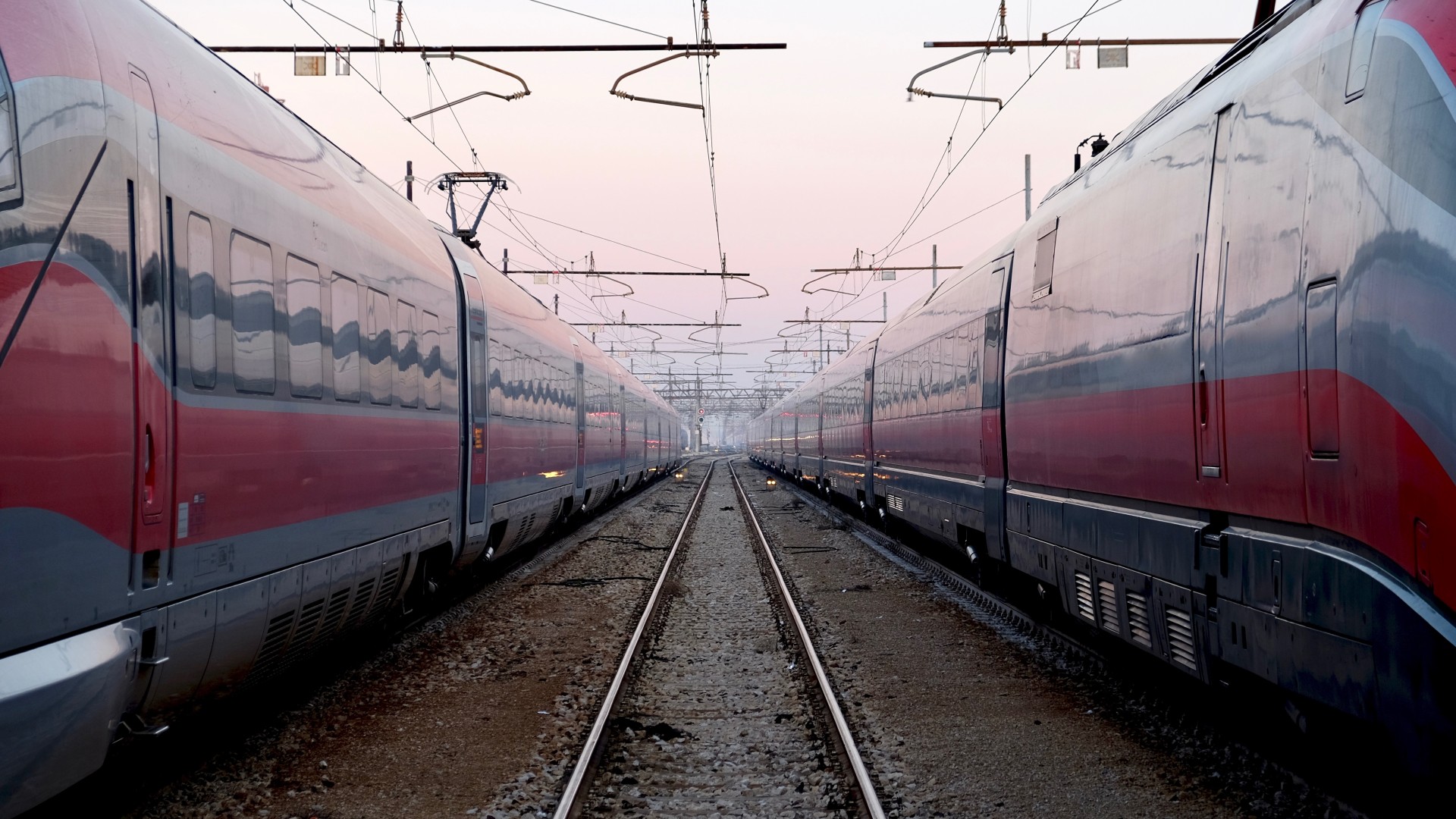 Modern trains on parallel tracks at dusk.