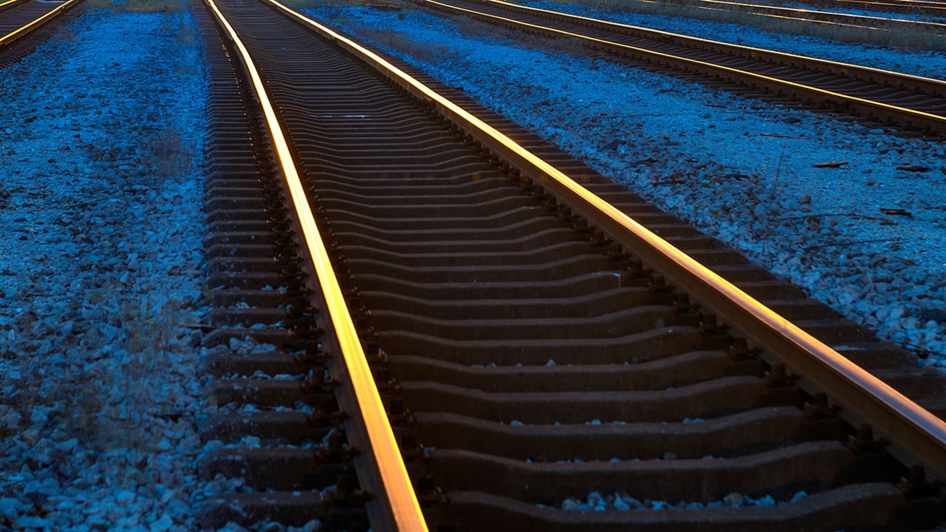 Railway tracks illuminated at dusk, gravel bed.