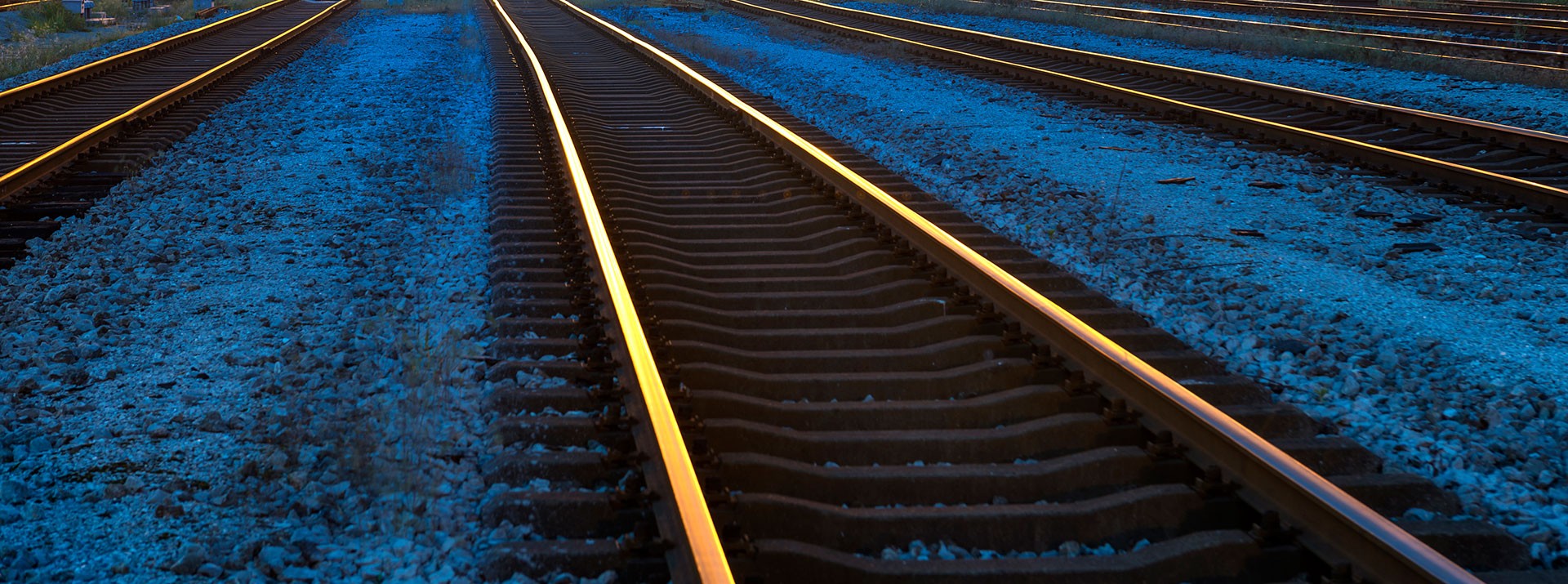 Railway tracks illuminated at dusk, gravel bed.