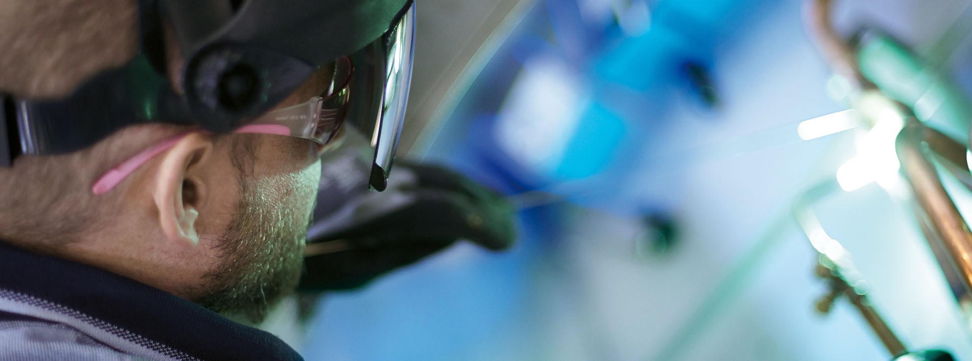 Welder focused on metalwork with protective gear.