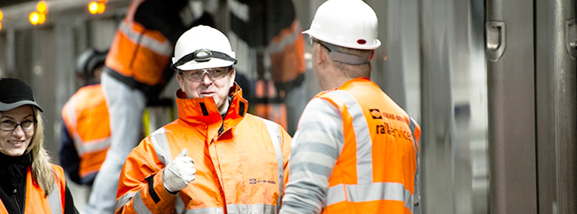 Employees wearing safety gear discussing in workshop.