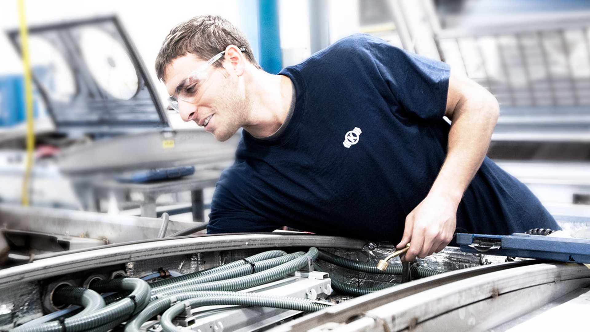Employee inspecting machinery in manufacturing facility.