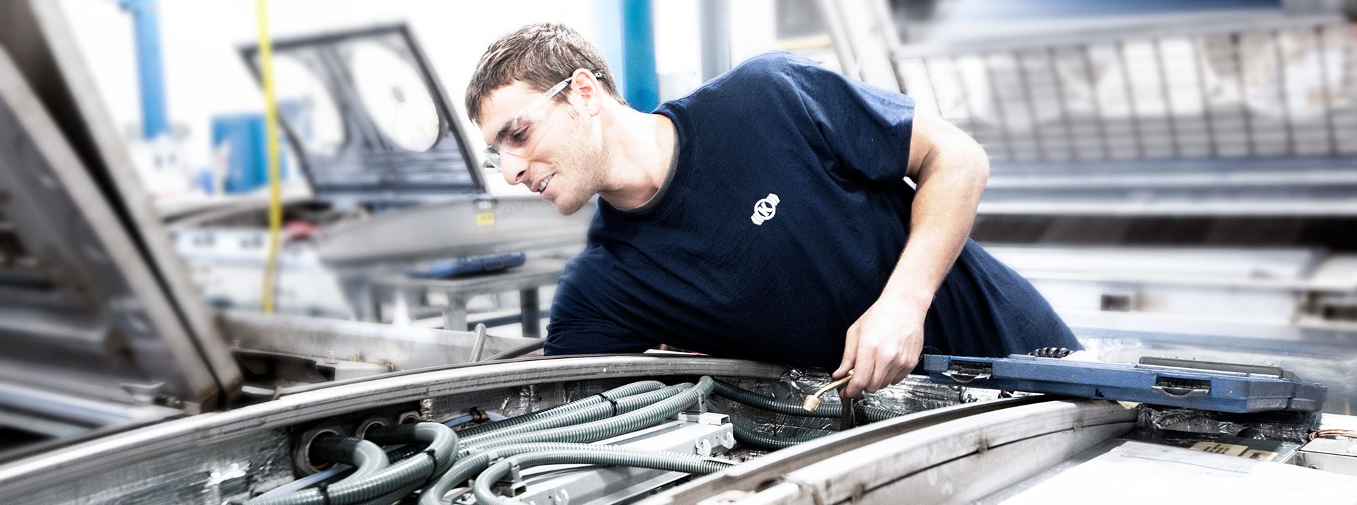Employee inspecting machinery in manufacturing facility.