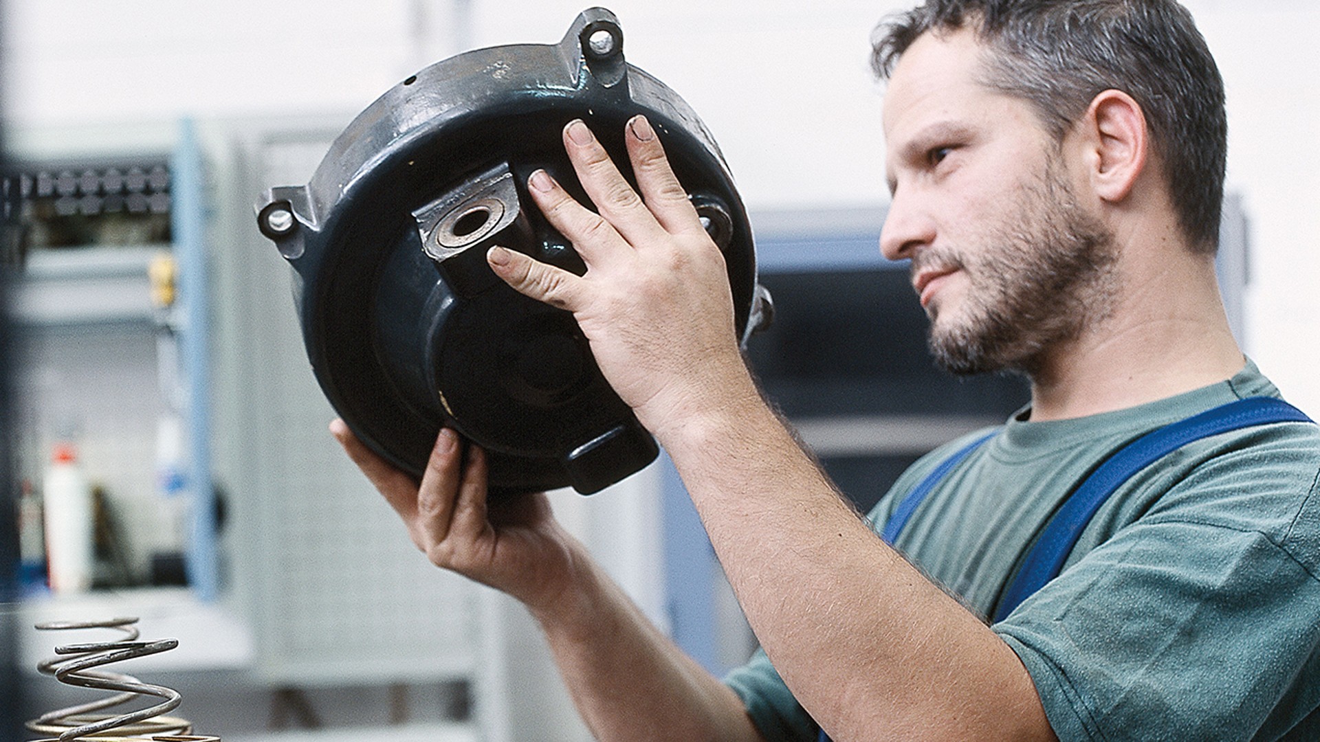Man inspecting a mechanical component in workshop.
