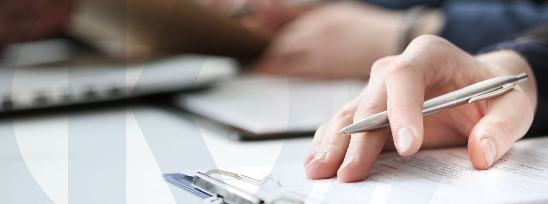 Hands holding a pen over documents on