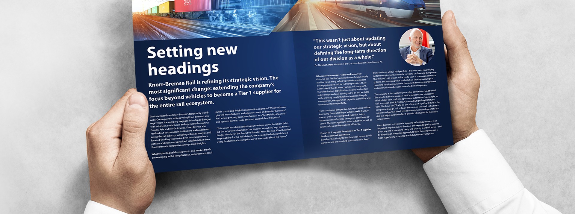 Two hands holding the informer and the page "setting new headings" is shown.