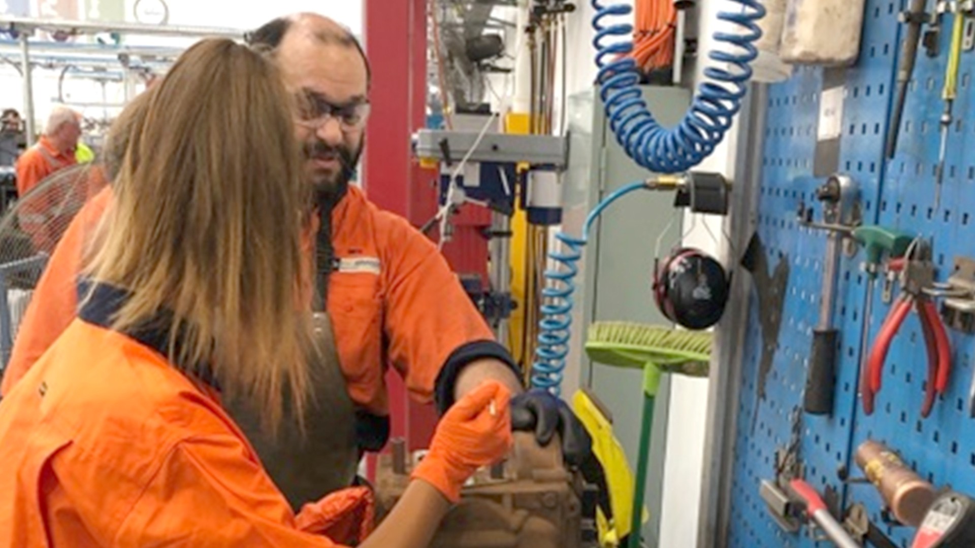 Employees collaborating on machinery in industrial workshop.