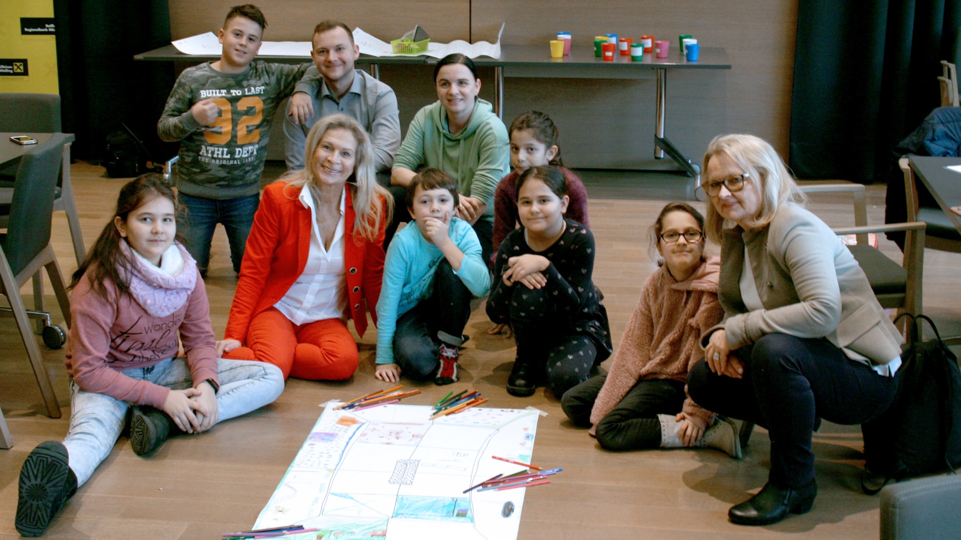 Group of children and adults with drawings.