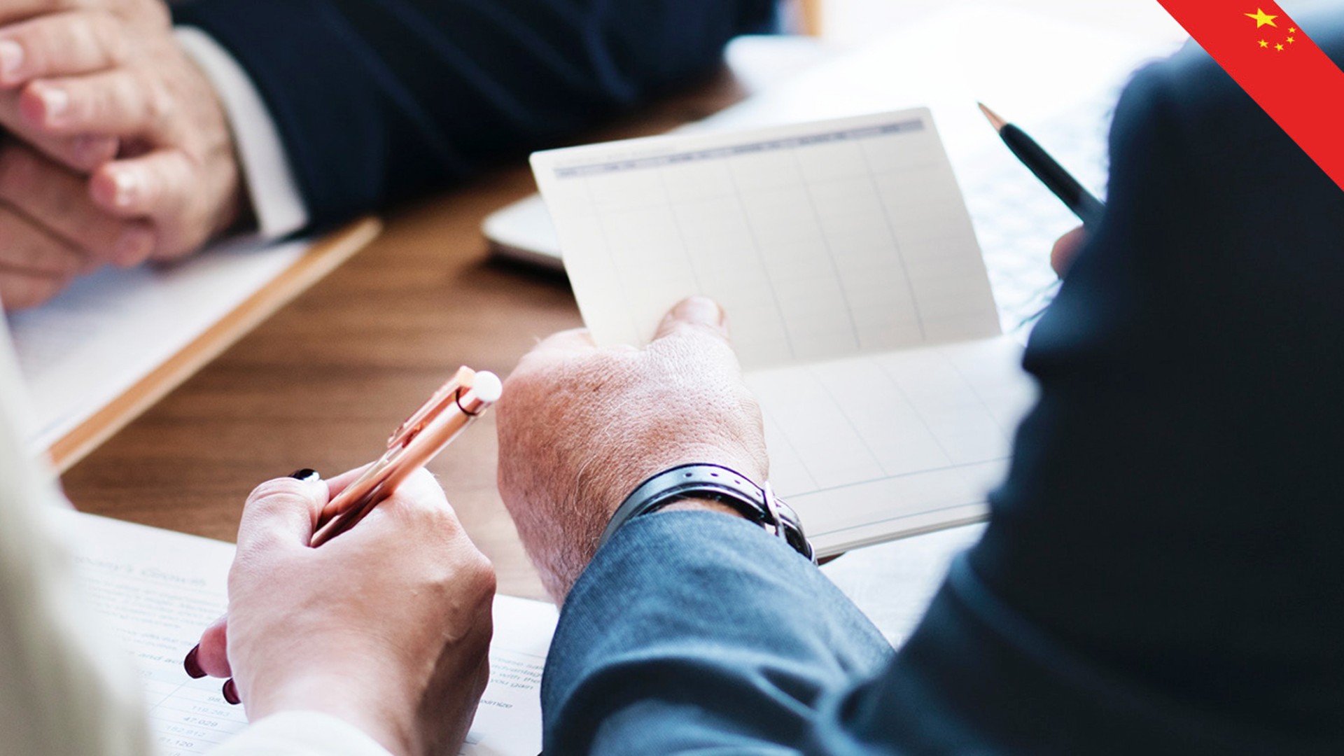 Business meeting with hands and notepad visible.