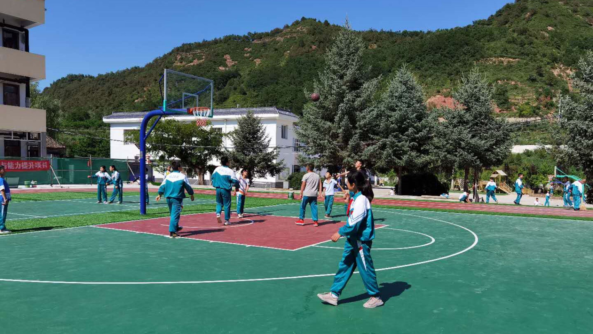 Students playing basketball on school playground.
