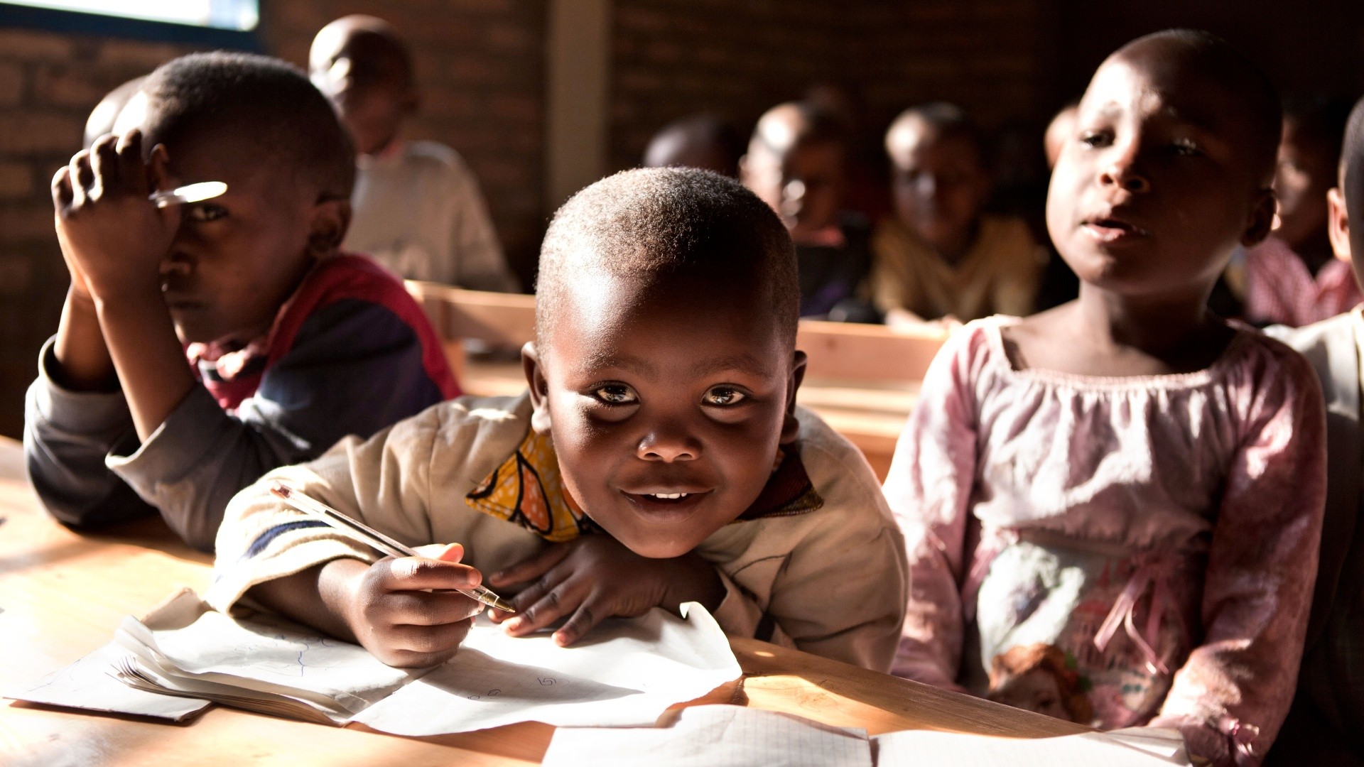 Children engaged in classroom learning, smiling faces.