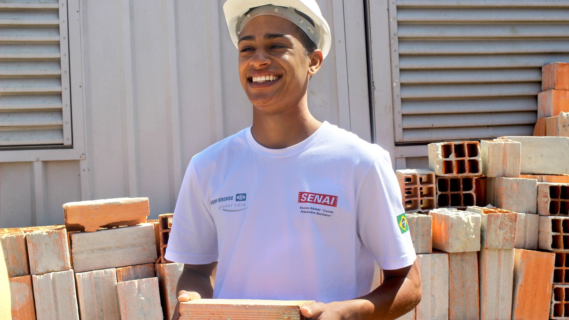 Smiling young man holding construction bricks outdoors.