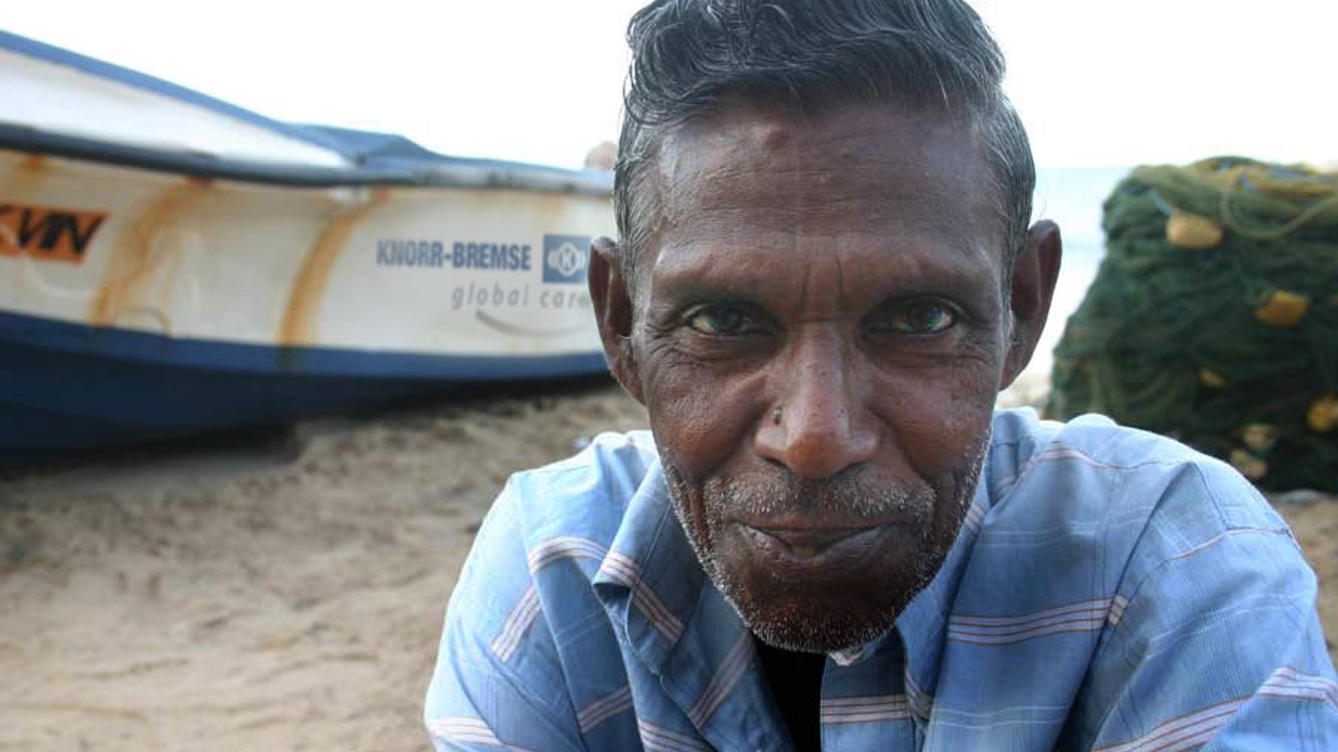 Smiling elderly man near fishing boat.